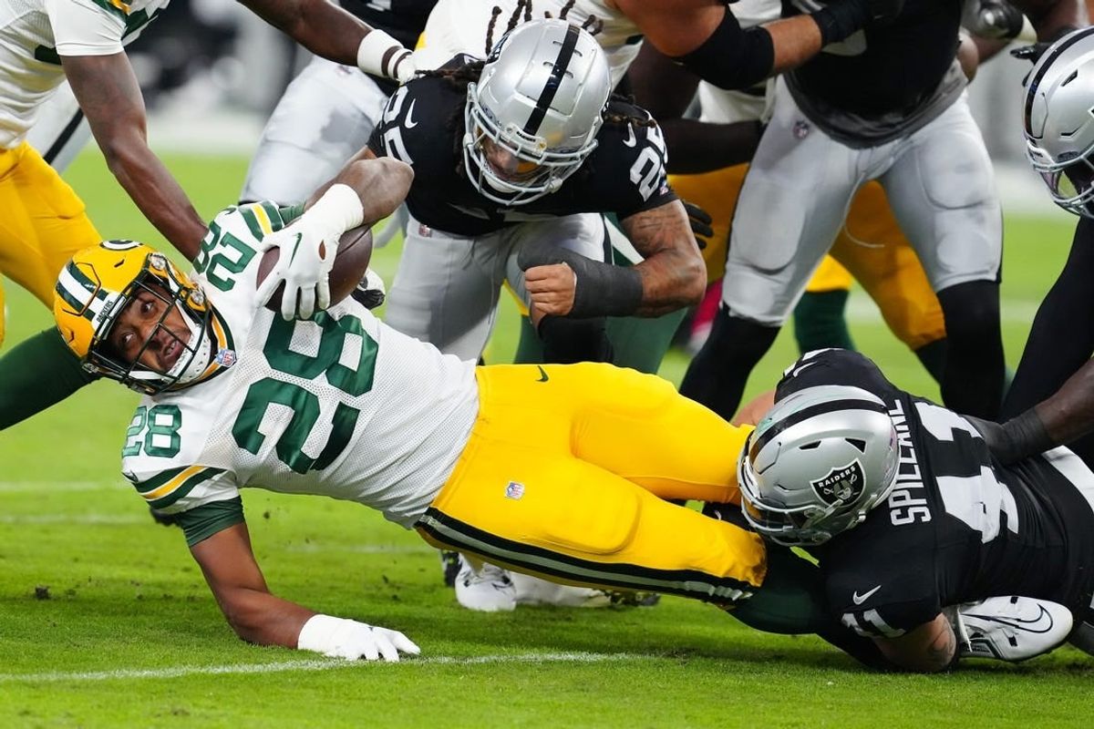 Oct 9, 2023; Paradise, Nevada, USA; Green Bay Packers running back AJ Dillon (28) is tackled by Las Vegas Raiders linebacker Robert Spillane (41) during the first quarter at Allegiant Stadium.
