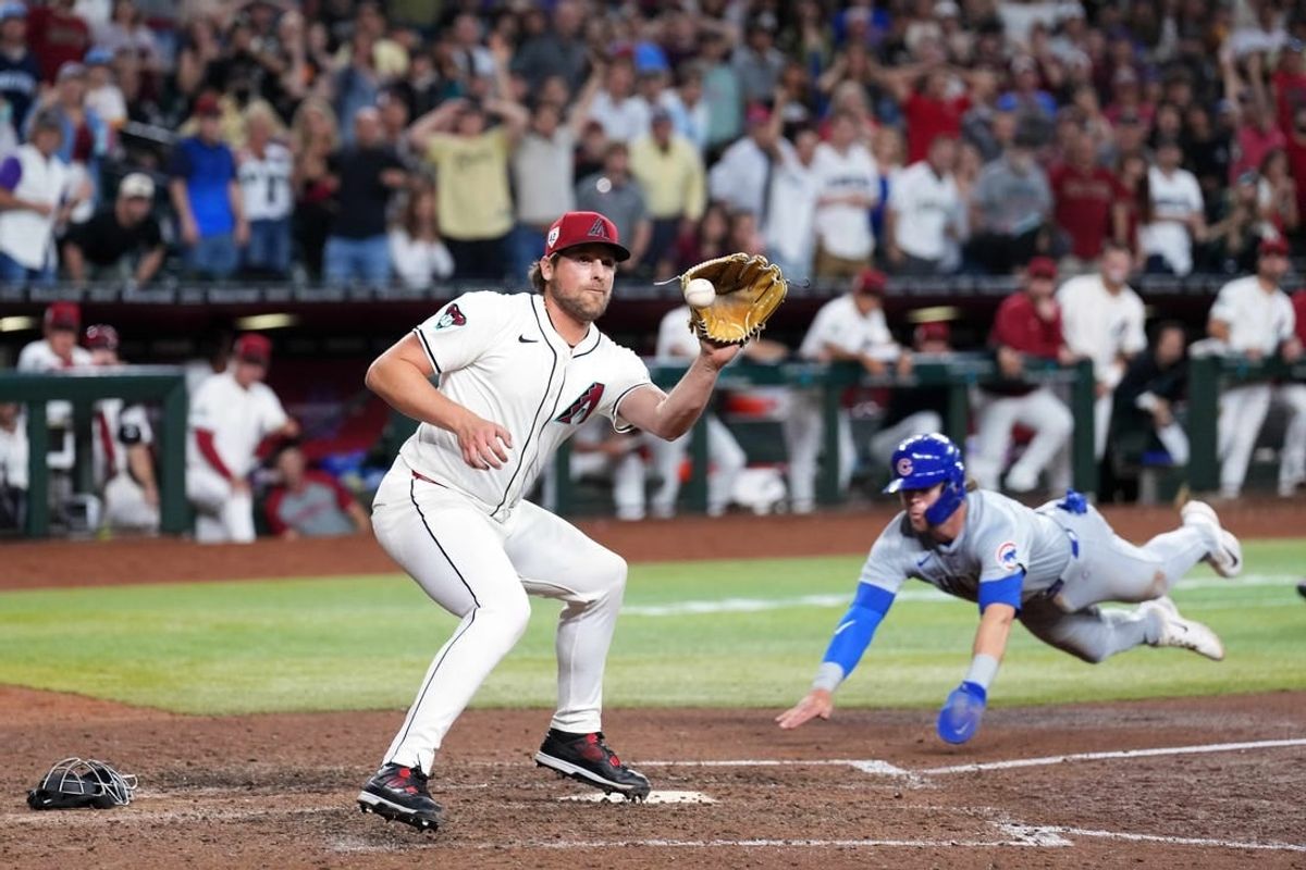 Apr 15, 2024; Phoenix, Arizona, USA; Chicago Cubs second baseman Nico Hoerner beats a throw to Arizona Diamondbacks pitcher Kevin Ginkel to score a run during the ninth inning at Chase Field. All players wore number 42 to commemorate Jackie Robinson Day.