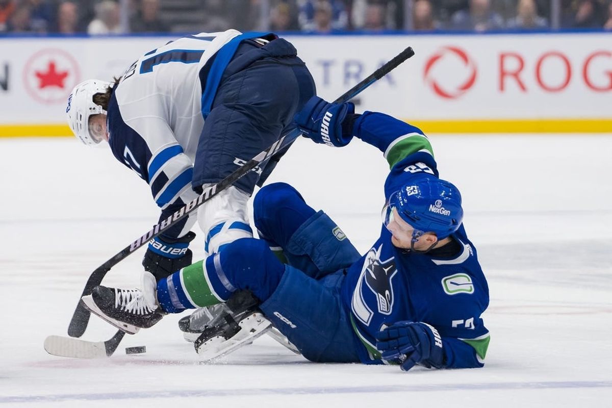 Mar 9, 2024; Vancouver, British Columbia, CAN; Winnipeg Jets forward Adam Lowry (17) checks Vancouver Canucks forward Teddy Blueger (53) in the first period at Rogers Arena.