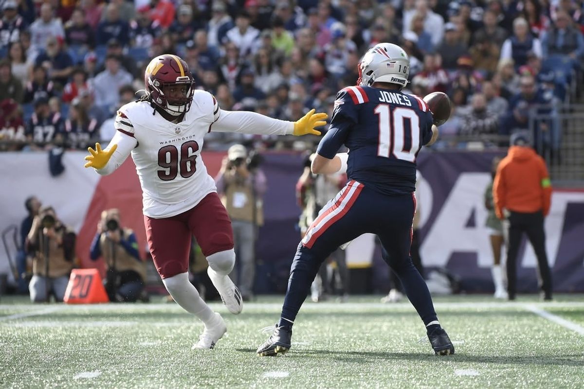 Nov 5, 2023; Foxborough, Massachusetts, USA;  New England Patriots quarterback Mac Jones (10) throws the ball away while Washington Commanders defensive end James Smith-Williams (96) defends during the first half at Gillette Stadium.