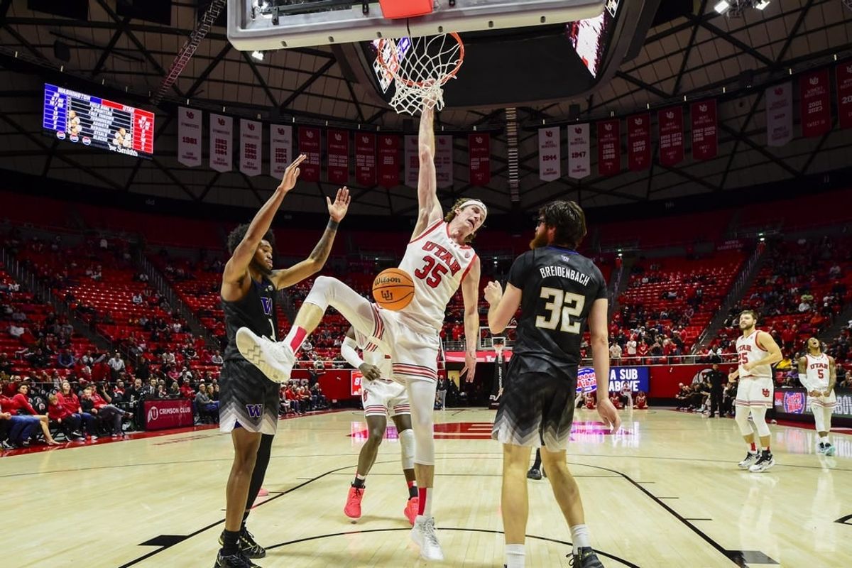 Dec 31, 2023; Salt Lake City, Utah, USA; Utah Utes center Branden Carlson (35) hangs onto the basket after dunking over Washington Huskies forward Wilhelm Breidenbach (32) during the second half at the the Jon M. Huntsman Center.