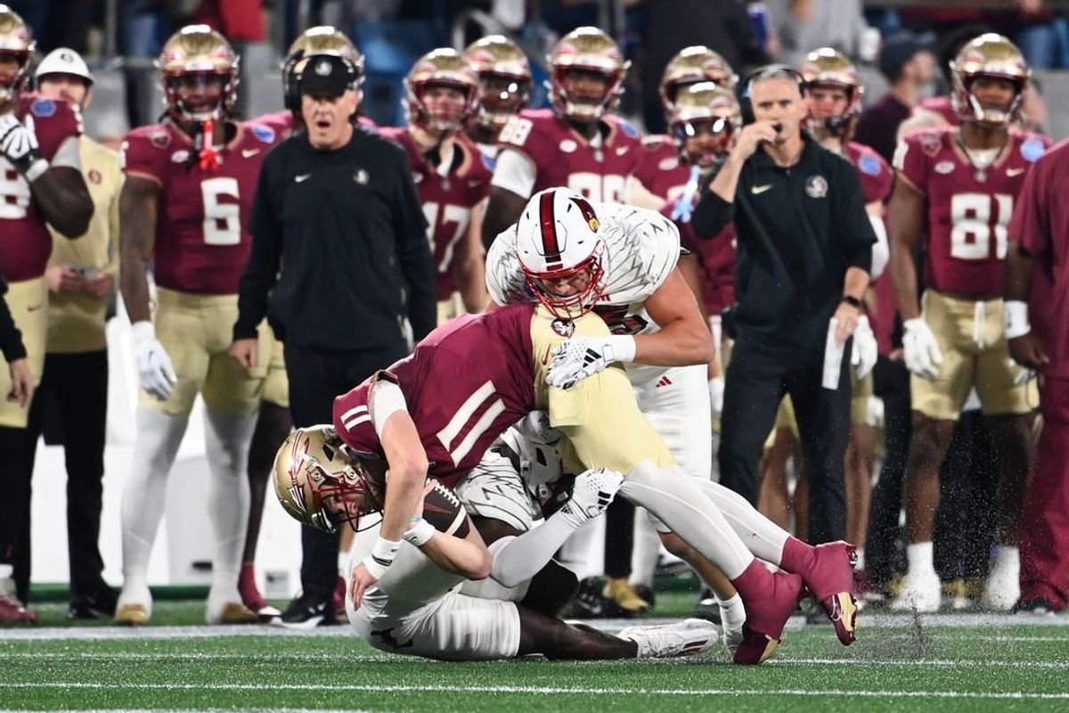 Dec 2, 2023; Charlotte, NC, USA; Florida State Seminoles quarterback Brock Glenn (11) is tackled by Louisville Cardinals defensive lineman Mason Reiger (95) and defensive back Quincy Riley (3) as he runs the ball in the second quarter at Bank of America Stadium.