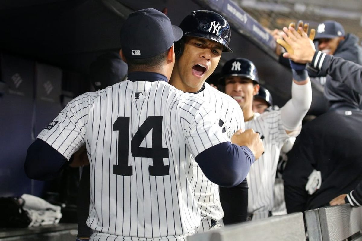 Apr 19, 2024; Bronx, New York, USA; New York Yankees right fielder Juan Soto (22) celebrates with second base Jahmai Jones (14) and teammates in the dugout after hitting a three run home run against the Tampa Bay Rays during the seventh inning at Yankee Stadium.