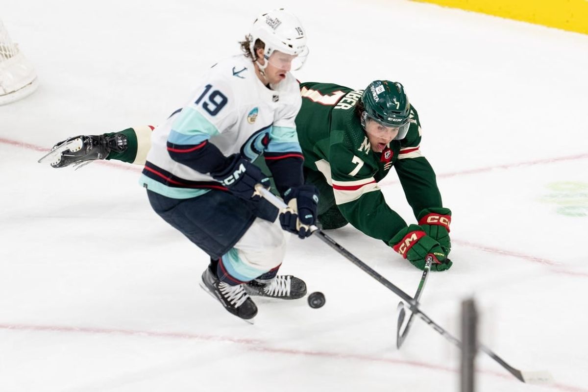 Apr 18, 2024; Saint Paul, Minnesota, USA; Minnesota Wild defenseman Brock Faber (7) knocks the puck aways from Seattle Kraken left wing Jared McCann (19) in the second period at Xcel Energy Center.