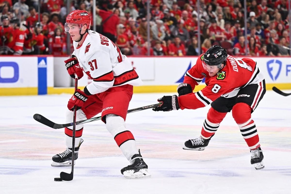 Apr 14, 2024; Chicago, Illinois, USA;  Carolina Hurricanes forward Andrei Svechnikov (37) controls the puck as Chicago Blackhawks forward Ryan Donato (8) attempts to defend from behind in the second period at United Center.