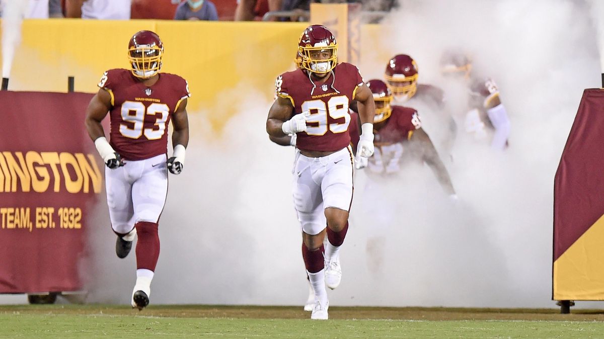 Chase Young and Jonathan Allen of the Washington Football Team run onto the field before the NFL preseason game against the Cincinnati Bengals at FedExField on August 20, 2021,  in Landover, Maryland.