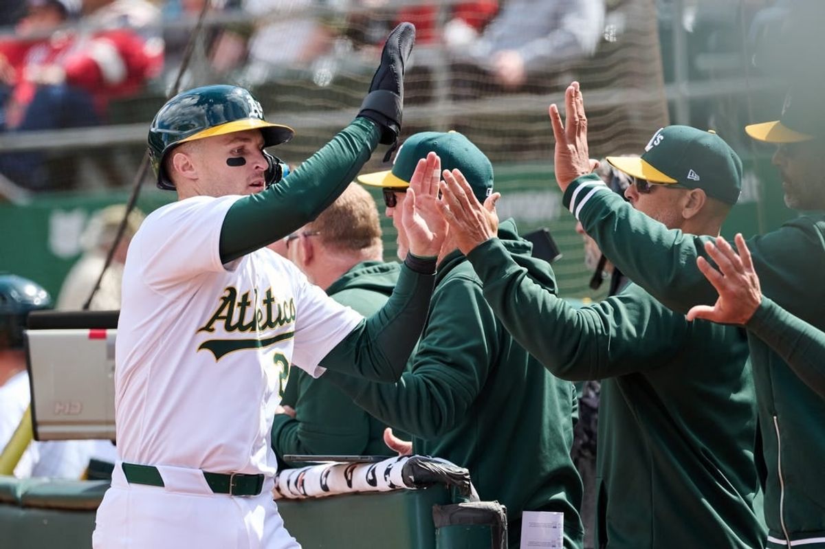 Apr 14, 2024; Oakland, California, USA; Oakland Athletics outfielder Tyler Nevin (26) shakes hands with his teammates after scoring a run against the Washington Nationals during the sixth inning at Oakland-Alameda County Coliseum.