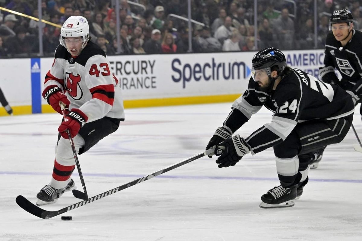 Mar 3, 2024; Los Angeles, California, USA;  New Jersey Devils defenseman Luke Hughes (43) and Los Angeles Kings center Phillip Danault (24) battle for the puck in the first period at Crypto.com Arena.