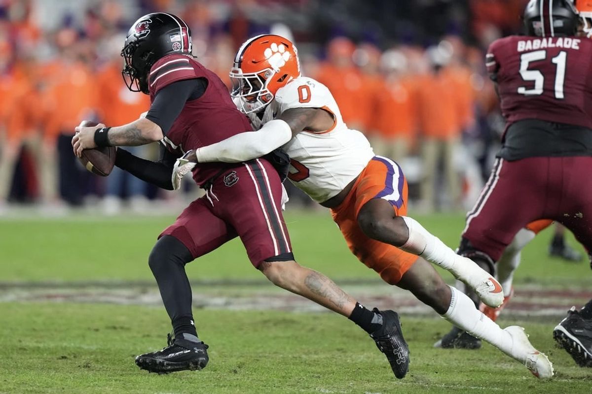Nov 25, 2023; Columbia, South Carolina, USA; South Carolina Gamecocks quarterback Spencer Rattler (7) is sacked by Clemson Tigers linebacker Barrett Carter (0) in the first half at Williams-Brice Stadium.