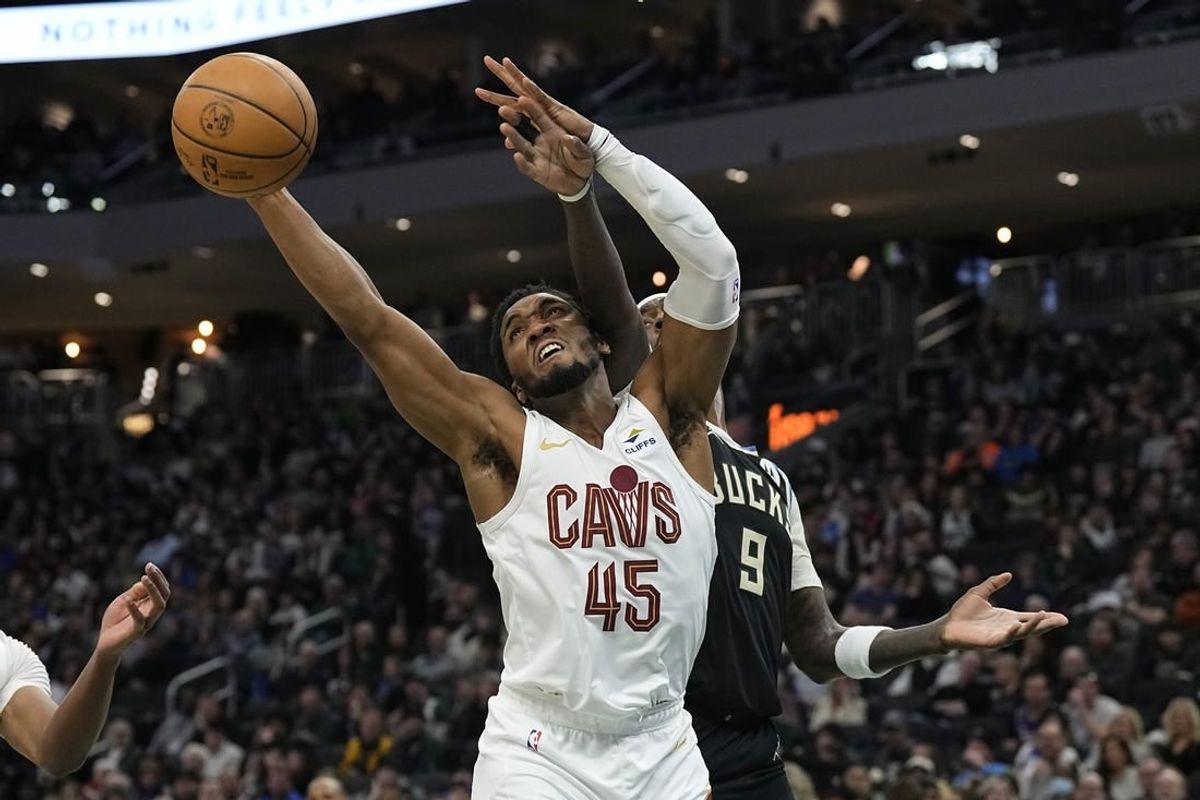 Jan 26, 2024; Milwaukee, Wisconsin, USA;  Cleveland Cavaliers guard Donovan Mitchell (45) reaches for a rebound in front of Milwaukee Bucks forward Bobby Portis (9) during the second quarter\ at Fiserv Forum.