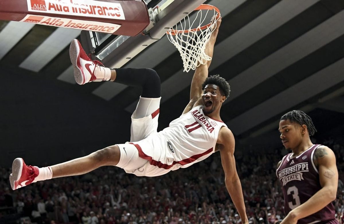 Feb 3, 2024; Tuscaloosa, Alabama, USA;  Alabama forward Mohamed Wague (11) hangs on the rim with a huge smile after dunking over Mississippi State guard Shakeel Moore (3) at Coleman Coliseum.