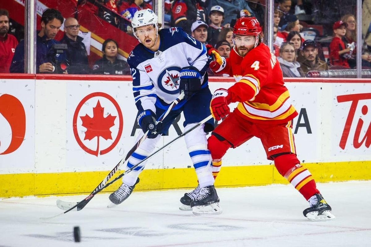 Oct 2, 2023; Calgary, Alberta, CAN; Winnipeg Jets center Mason Appleton (22) and Calgary Flames defenseman Rasmus Andersson (4) battle for the puck during the first period at Scotiabank Saddledome.