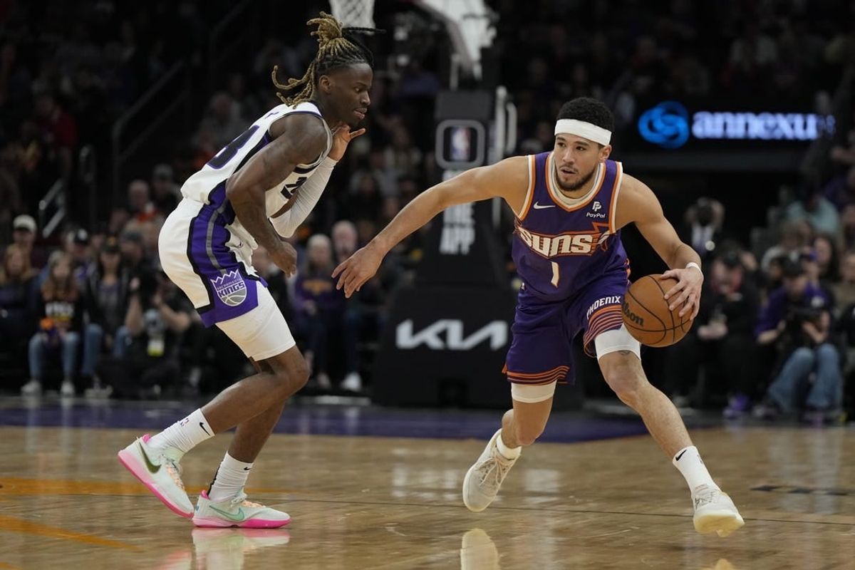Feb 13, 2024; Phoenix, Arizona, USA; Phoenix Suns guard Devin Booker (1) drives on Sacramento Kings guard Keon Ellis (23) in the first half at Footprint Center.