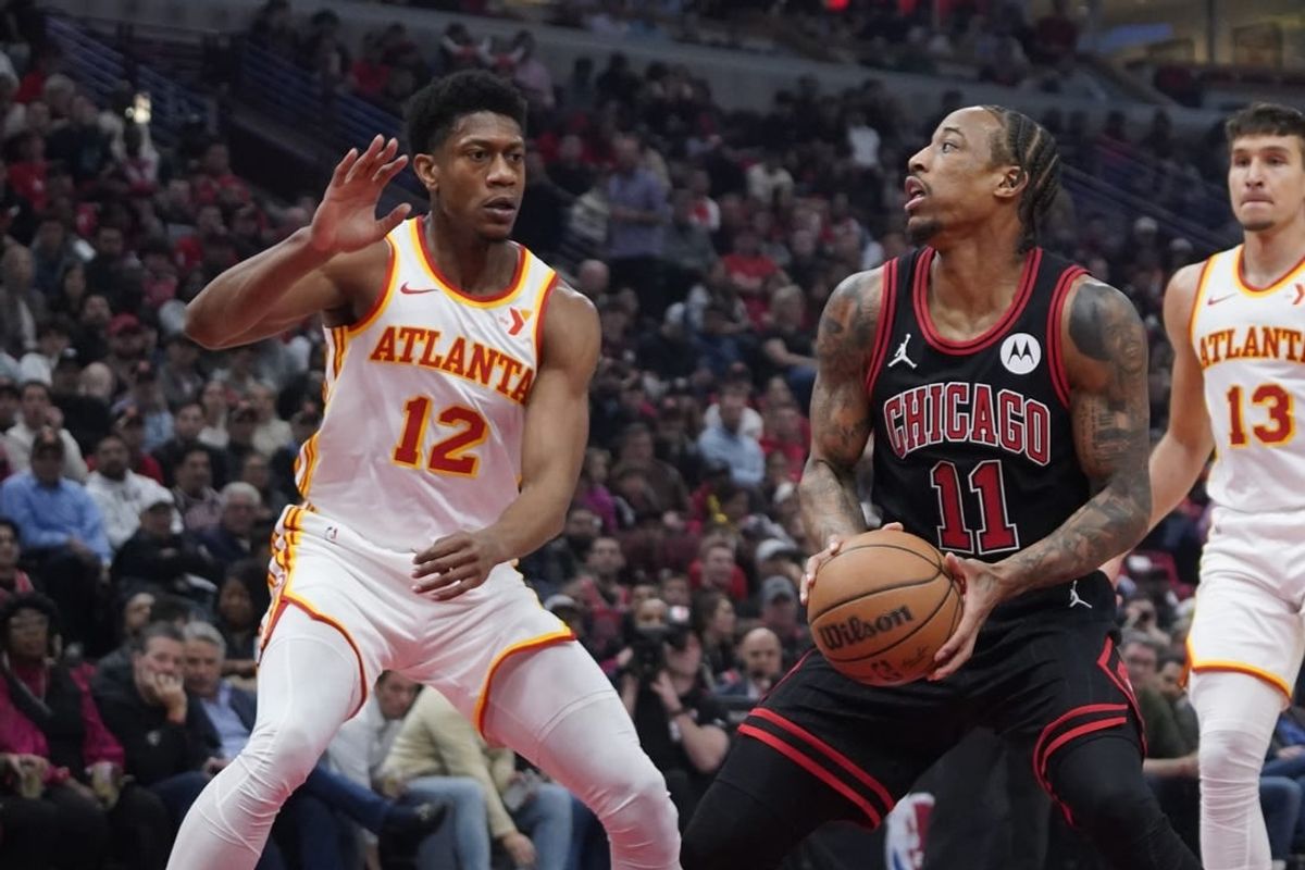 Apr 17, 2024; Chicago, Illinois, USA; Atlanta Hawks forward De'Andre Hunter (12) defends Chicago Bulls forward DeMar DeRozan (11) during the first quarter during a play-in game of the 2024 NBA playoffs at United Center.
