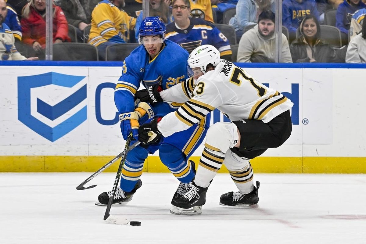 Jan 13, 2024; St. Louis, Missouri, USA;  St. Louis Blues center Jordan Kyrou (25) and Boston Bruins defenseman Charlie McAvoy (73) battle for the puck during the second period at Enterprise Center.