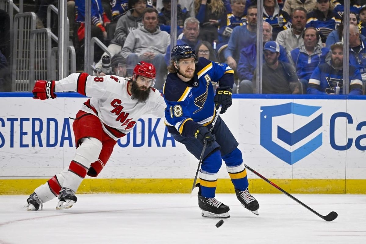 Apr 12, 2024; St. Louis, Missouri, USA;  St. Louis Blues center Robert Thomas (18) passes the puck as Carolina Hurricanes defenseman Brent Burns (8) defends during the third period at Enterprise Center.