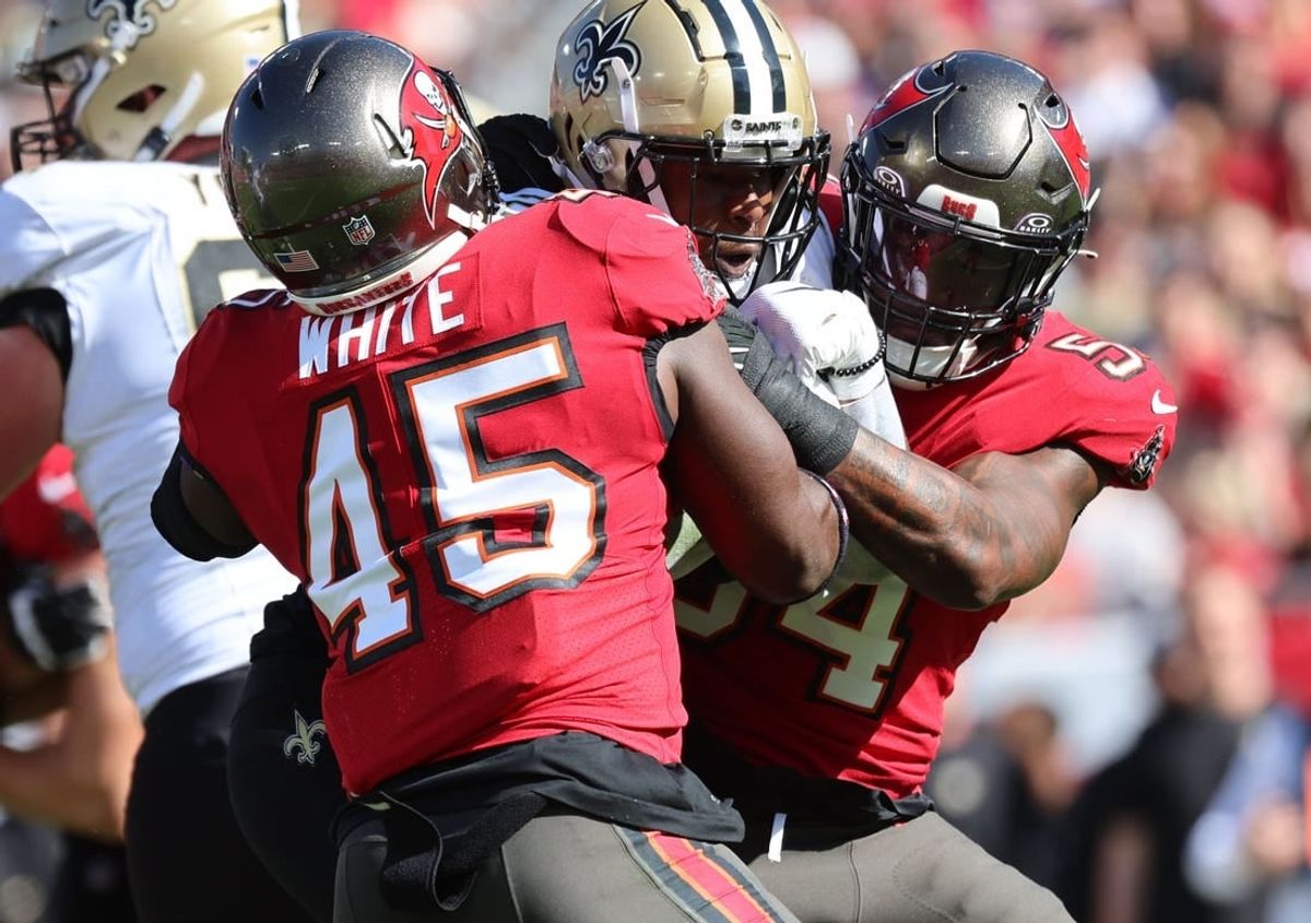 Dec 31, 2023; Tampa, Florida, USA; New Orleans Saints running back Jamaal Williams (21) runs with the ball as Tampa Bay Buccaneers linebacker Devin White (45) and linebacker Lavonte David (54) tackle during the first quarter at Raymond James Stadium.