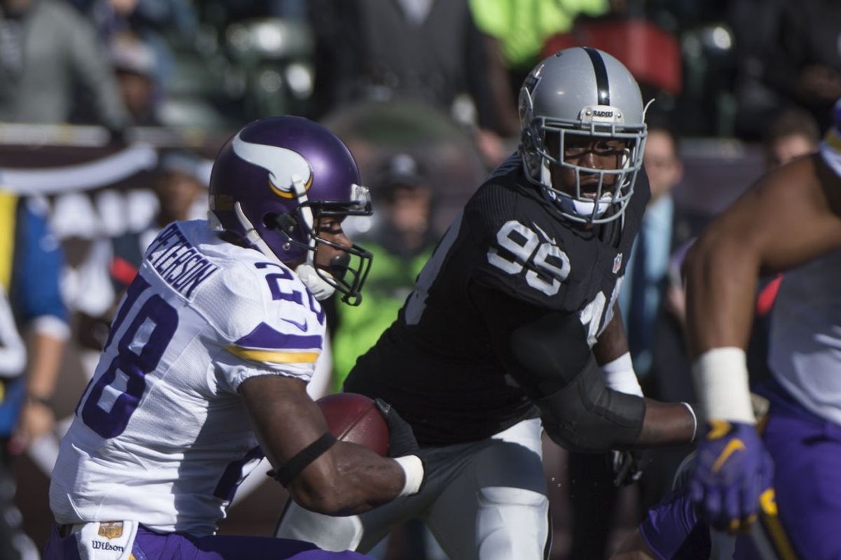 November 15, 2015; Oakland, CA, USA; Minnesota Vikings running back Adrian Peterson (28) runs with the football against Oakland Raiders outside linebacker Aldon Smith (99) during the first quarter at O.co Coliseum. Mandatory Credit: Kyle Terada-Imagn Images