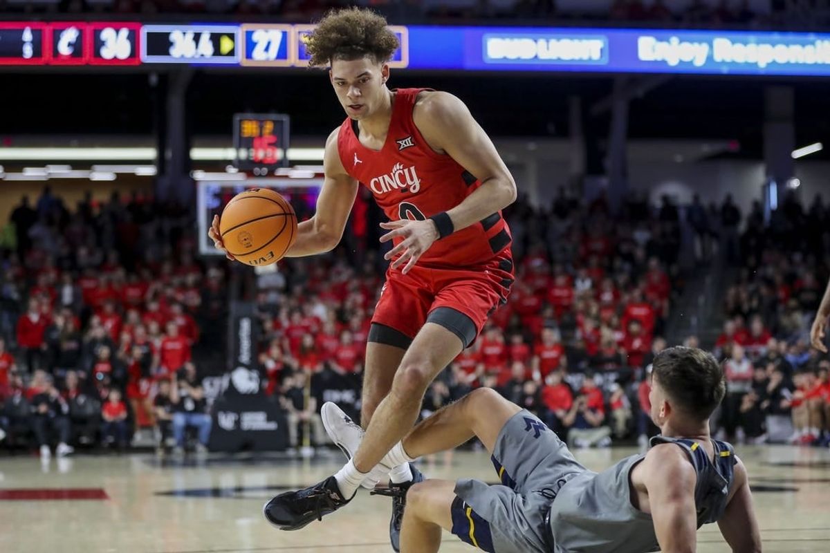 Mar 9, 2024; Cincinnati, Ohio, USA; Cincinnati Bearcats guard Dan Skillings Jr. (0) drives to the basket against West Virginia Mountaineers guard Kerr Kriisa (3) in the first half at Fifth Third Arena.
