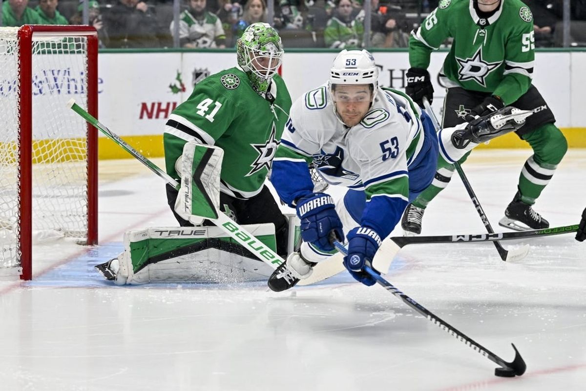 Dec 21, 2023; Dallas, Texas, USA; Vancouver Canucks center Teddy Blueger (53) is tripped up in front of Dallas Stars goaltender Scott Wedgewood (41) as he tires to control the puck during the first period at the American Airlines Center.