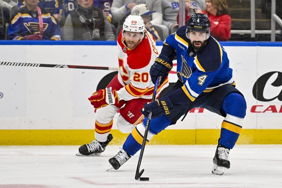 Mar 28, 2024; St. Louis, Missouri, USA;  St. Louis Blues defenseman Nick Leddy (4) controls the puck as Calgary Flames center Blake Coleman (20) gives chase during the first period at Enterprise Center.
