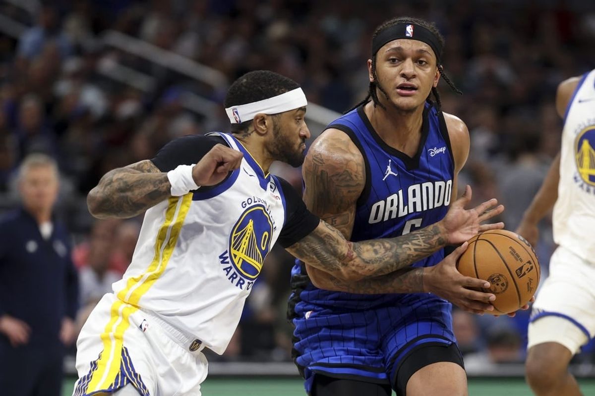 Mar 27, 2024; Orlando, Florida, USA;  Orlando Magic forward Paolo Banchero (5) drives the ball past Golden State Warriors guard Gary Payton II (0) in the second quarter at the Kia Center.