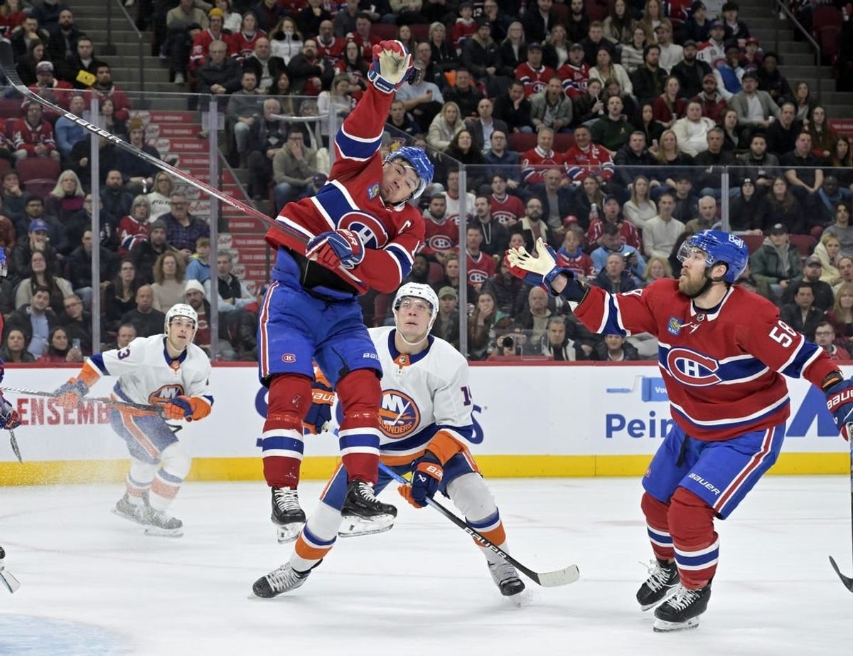 Dec 16, 2023; Montreal, Quebec, CAN; Montreal Canadiens forward Nick Suzuki (14) jumps to reach the puck during the first period of the game against the New York Islanders at the Bell Centre.