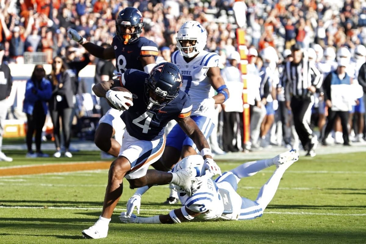 Nov 18, 2023; Charlottesville, Virginia, USA; Virginia Cavaliers wide receiver Malik Washington (4) scores a touchdown as Duke Blue Devils safety Jaylen Stinson (2) chases during the first quarter at Scott Stadium.