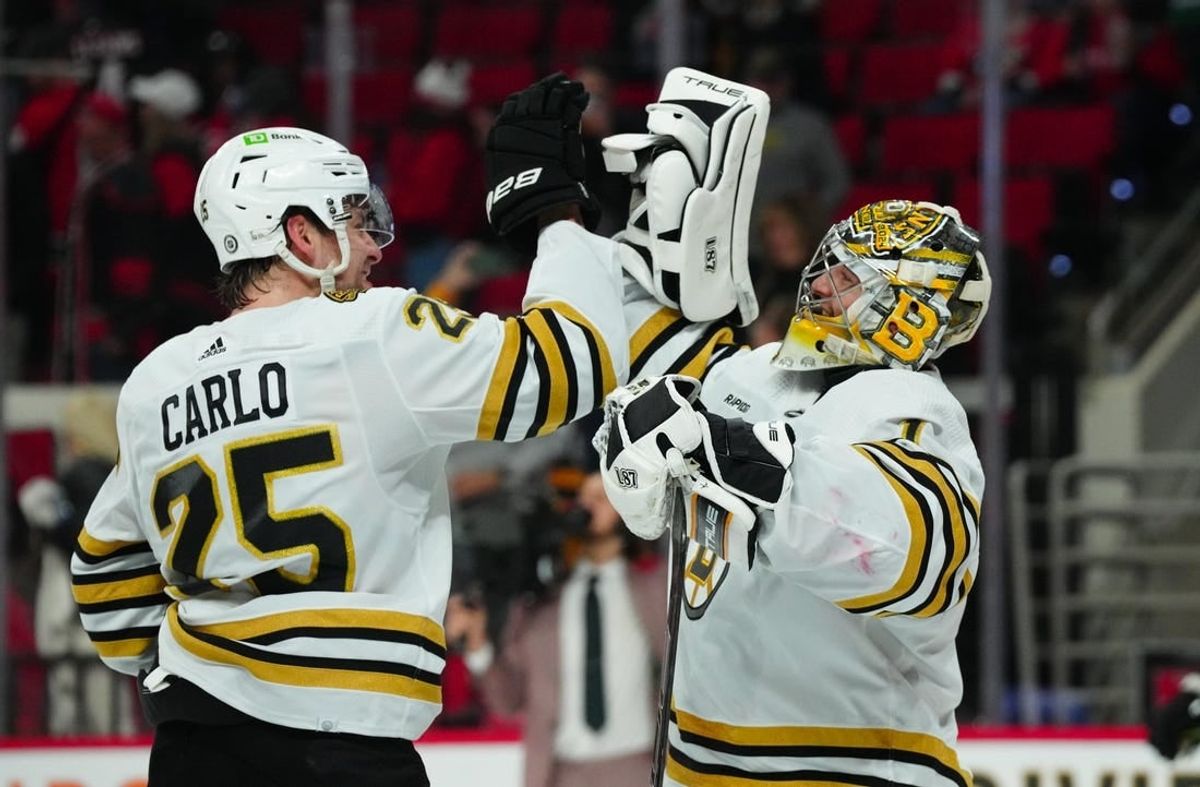 Apr 4, 2024; Raleigh, North Carolina, USA; Boston Bruins goaltender Jeremy Swayman (1) and defenseman Brandon Carlo (25) celebrate their victory against the Carolina Hurricanes at PNC Arena.