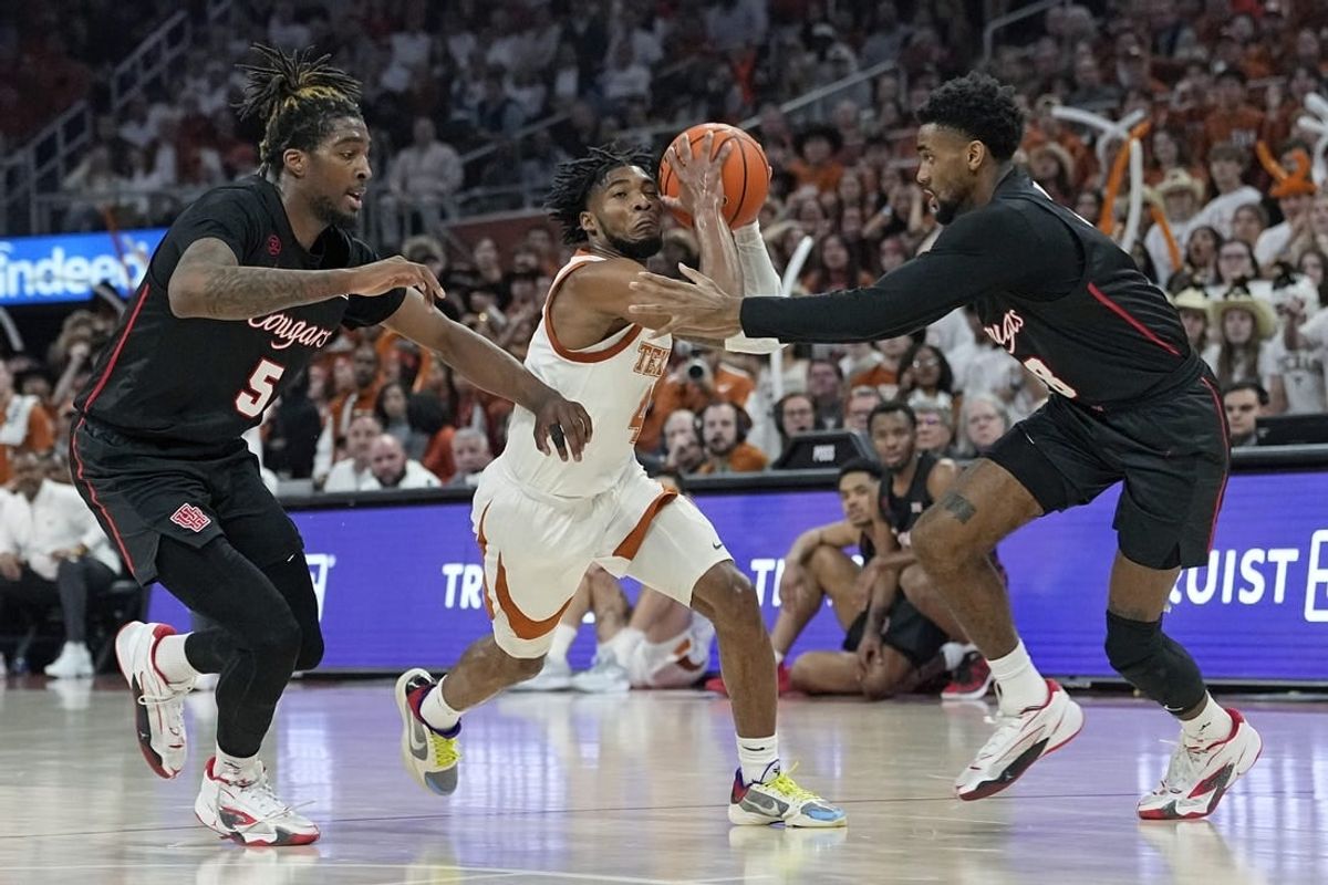 Jan 29, 2024; Austin, Texas, USA; Texas Longhorns guard Tyrese Hunter (4) drives to the basket between Houston Cougars forward Ja'Vier Francis (5) and guard Mylik Wilson (8) during the first half at Moody Center.