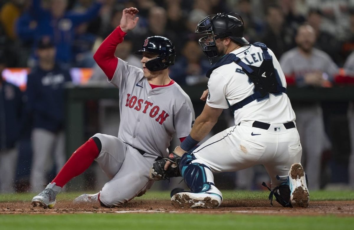 Mar 28, 2024; Seattle, Washington, USA; Boston Red Sox right fielder Tyler O'Neill (17) scores a run after a throw gets past Seattle Mariners catcher Cal Raleigh (29) during the fourth inning at T-Mobile Park.