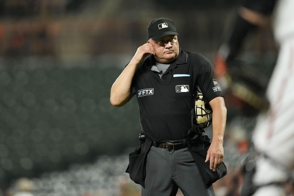 Sep 6, 2022; Baltimore, Maryland, USA; Umpire Jeff Nelson listens for the results of an instant replay review of Toronto Blue Jays shortstop Bo Bichette's (not pictured) hit against the Baltimore Orioles during the third inning at Oriole Park at Camden Yards. The review determined that Bichette hit a home run.