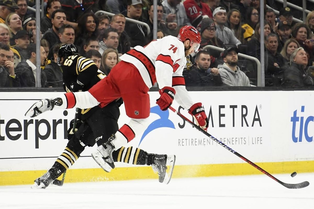 Apr 9, 2024; Boston, Massachusetts, USA; Boston Bruins defenseman Andrew Peeke (52) checks Carolina Hurricanes defenseman Jaccob Slavin (74) during the first period at TD Garden.