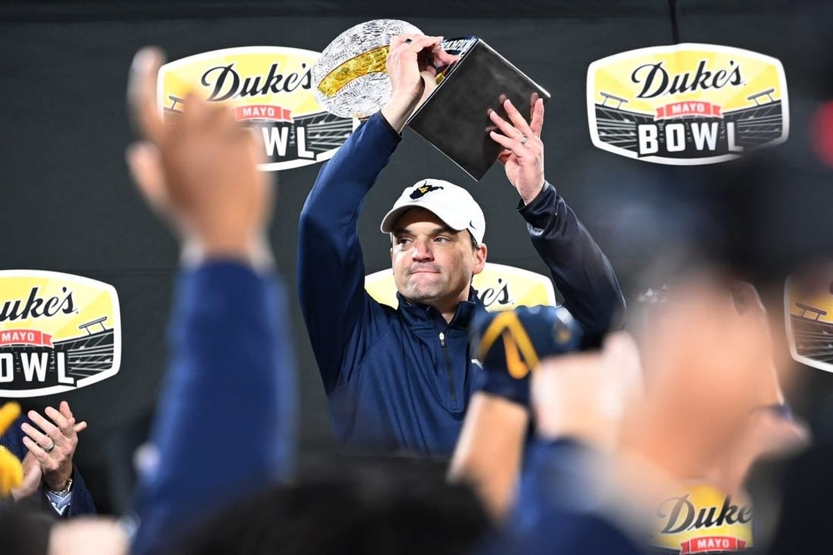 Dec 27, 2023; Charlotte, NC, USA; West Virginia Mountaineers head coach Neal Brown holds up the championship trophy after the game at Bank of America Stadium.