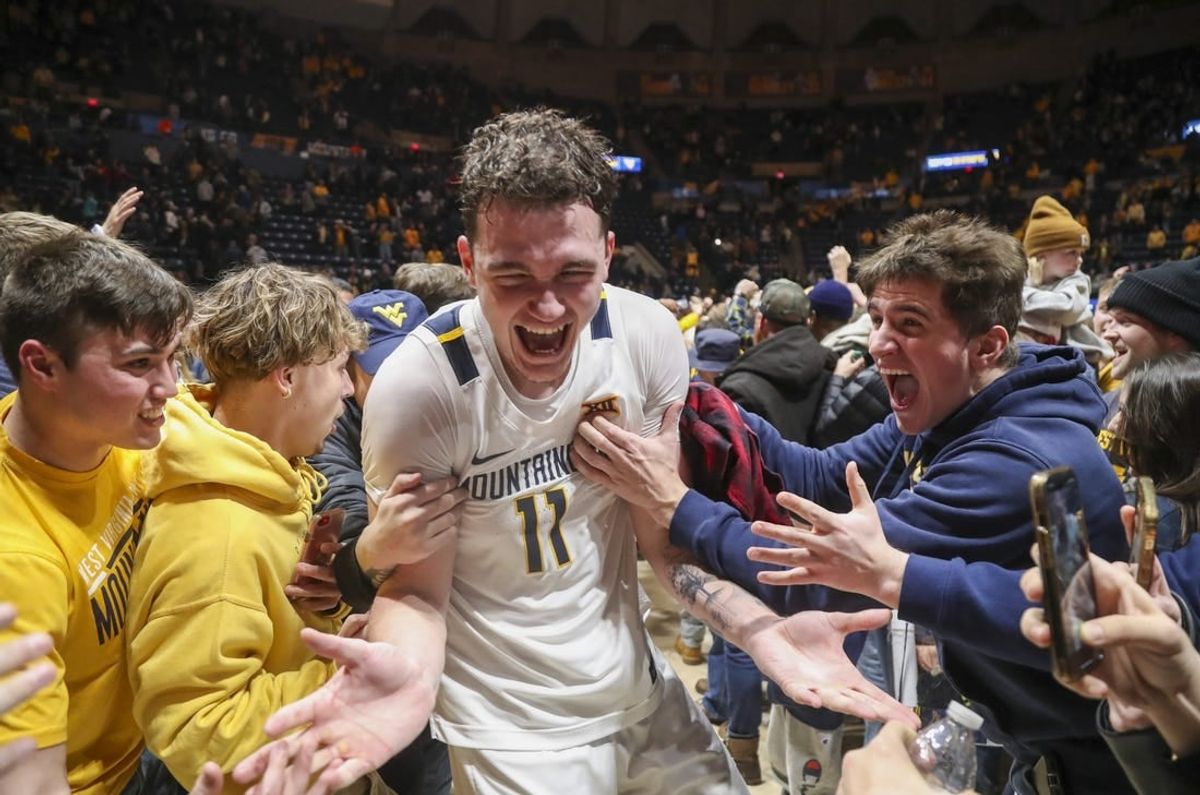 Jan 20, 2024; Morgantown, West Virginia, USA; West Virginia Mountaineers forward Quinn Slazinski (11) celebrates with students after defeating the Kansas Jayhawks at WVU Coliseum.