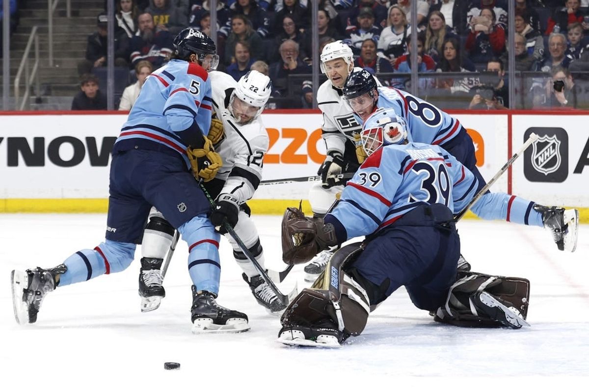 Apr 1, 2024; Winnipeg, Manitoba, CAN; Winnipeg Jets defenseman Brenden Dillon (5) and Los Angeles Kings left wing Kevin Fiala (22) scramble for the puck in front of Winnipeg Jets goaltender Laurent Brossoit (39) in the first period at Canada Life Centre.