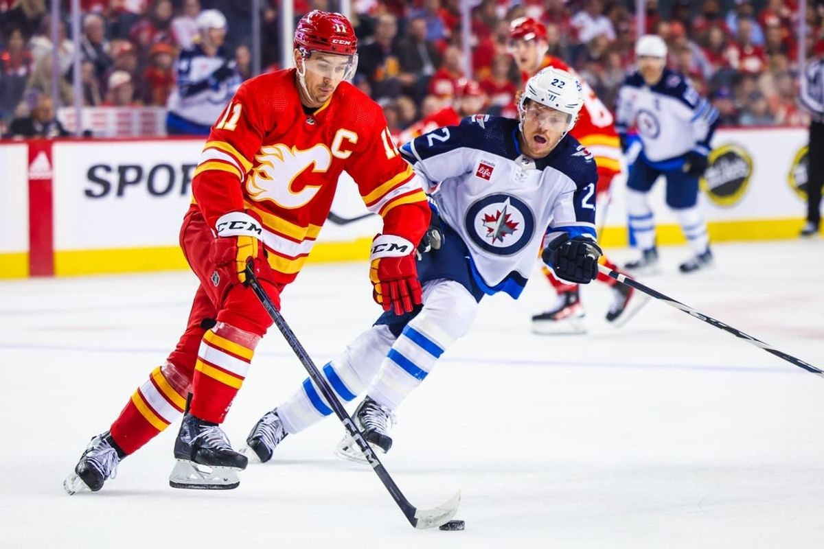 Oct 11, 2023; Calgary, Alberta, CAN; Calgary Flames center Mikael Backlund (11) controls the puck against Winnipeg Jets center Mason Appleton (22) during the first period at Scotiabank Saddledome.