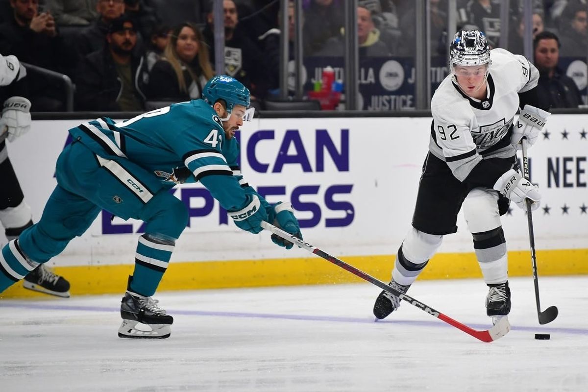 Jan 22, 2024; Los Angeles, California, USA; Los Angeles Kings defenseman Brandt Clarke (92) moves the puck against San Jose Sharks center Tomas Hertl (48) during the second period at Crypto.com Arena.
