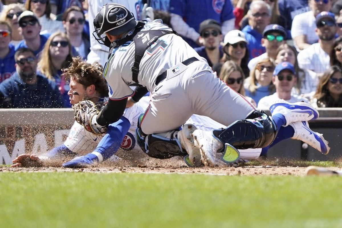Apr 21, 2024; Chicago, Illinois, USA; Miami Marlins catcher Nick Fortes (4) tags out Chicago Cubs second baseman at home plate during the fourth inning Nico Hoerner (2) at Wrigley Field.