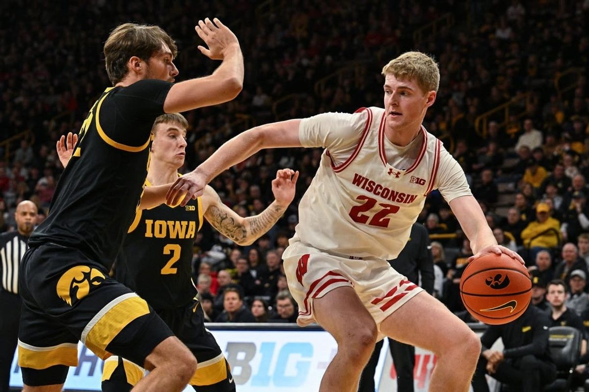 Feb 17, 2024; Iowa City, Iowa, USA; Wisconsin Badgers forward Steven Crowl (22) controls the ball as Iowa Hawkeyes forward Owen Freeman (32) and guard Brock Harding (2) defend during the first half at Carver-Hawkeye Arena.