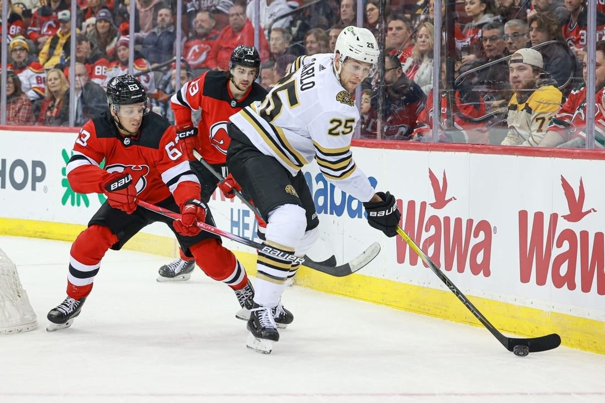 Dec 13, 2023; Newark, New Jersey, USA; Boston Bruins defenseman Brandon Carlo (25) skates with the puck as New Jersey Devils left wing Jesper Bratt (63) and center Nico Hischier (13) defend during the first period at Prudential Center.