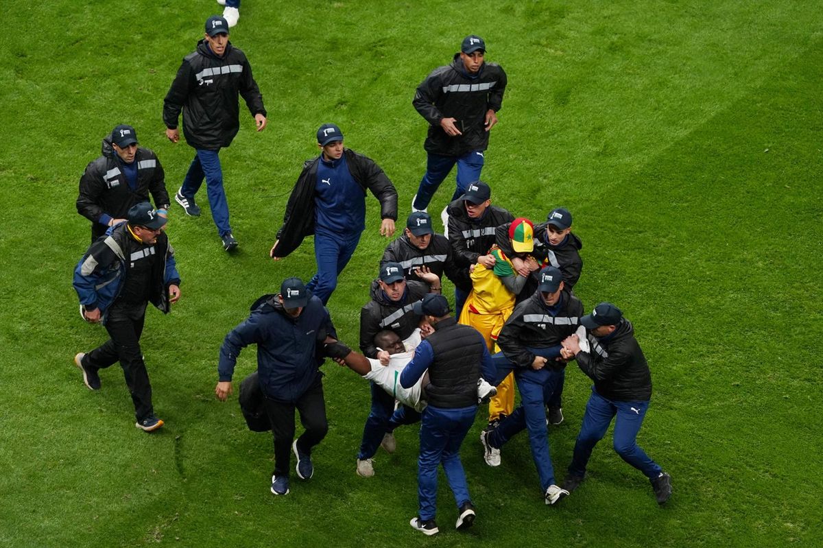 Security staff tackle Senegal fans who invaded the pitch after Morocco were awarded a penalty following a VAR review during the Africa Cup of Nations final in Rabat on Jan. 18, 2026.