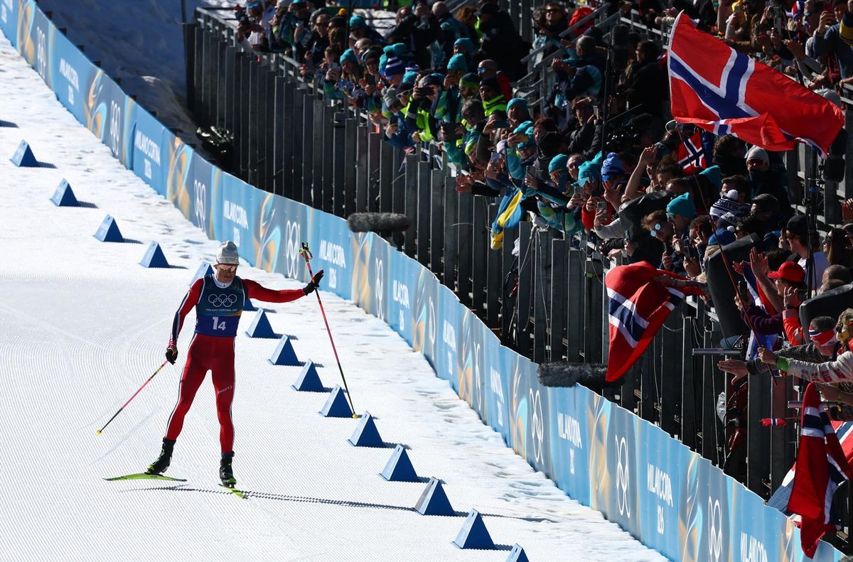 Johannes Klaebo of Norway celebrates with fans before crossing the finish line to win the Winter Olympics gold medal in the men's 4x7.5 km relay on Sunday in Lago, Italy.