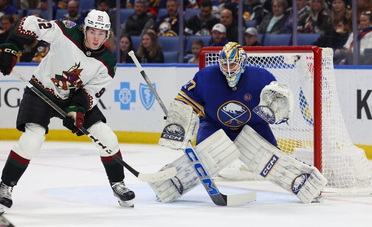 Dec 11, 2023; Buffalo, New York, USA;  Arizona Coyotes center Logan Cooley (92) and Buffalo Sabres goaltender Devon Levi (27) look for the puck during the first period at KeyBank Center.