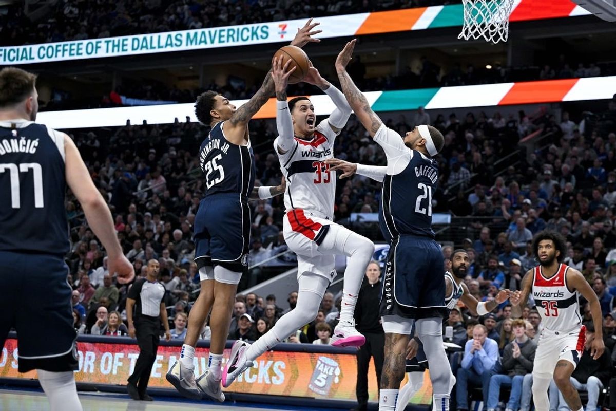 Feb 12, 2024; Dallas, Texas, USA; Washington Wizards forward Kyle Kuzma (33) drives to the basket between Dallas Mavericks forward P.J. Washington (25) and center Daniel Gafford (21) during the second quarter at the American Airlines Center.