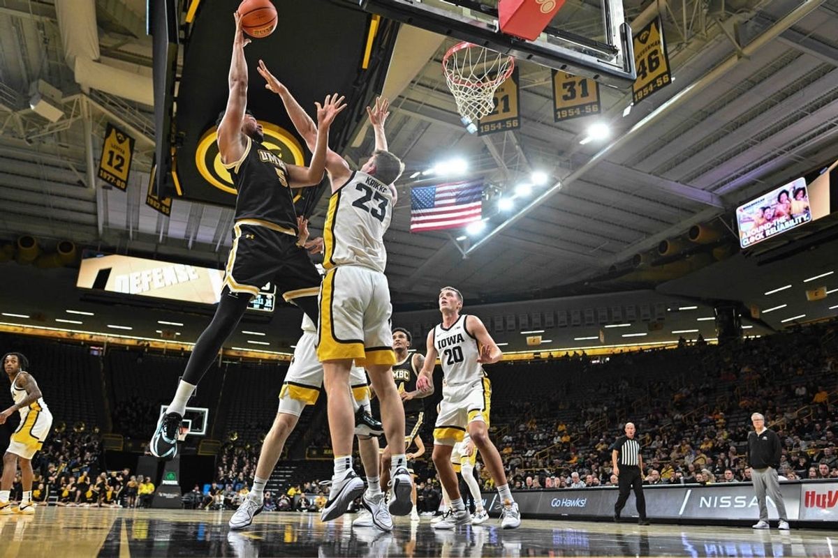 Dec 20, 2023; Iowa City, Iowa, USA; UMBC Retrievers center Max Lorca-Lloyd (5) shoots the ball over Iowa Hawkeyes forward Ben Krikke (23) and forward Payton Sandfort (20) defend during the first half at Carver-Hawkeye Arena.