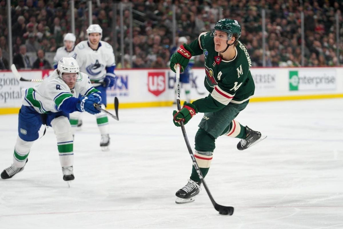 Feb 19, 2024; Saint Paul, Minnesota, USA; Minnesota Wild center Joel Eriksson Ek (14) shoots as Vancouver Canucks right wing Conor Garland (8) defends in the second period at Xcel Energy Center.