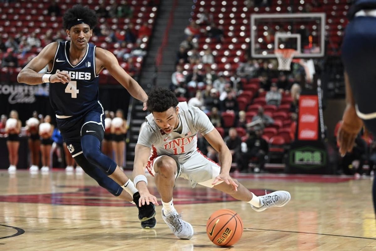 Jan 13, 2024; Las Vegas, Nevada, USA; UNLV Rebels guard Dedan Thomas Jr. (11) falls near Utah State Aggies guard Ian Martinez (4) during the first half at Thomas & Mack Center.