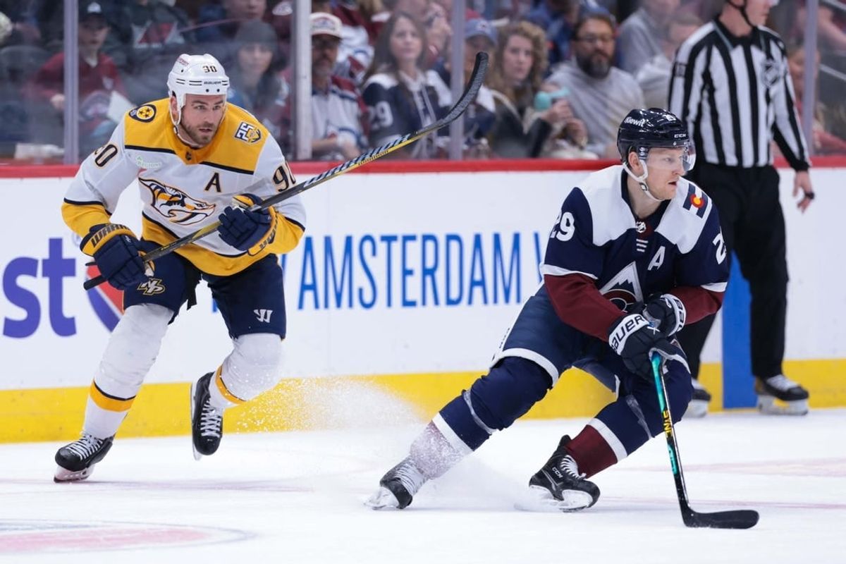 Mar 30, 2024; Denver, Colorado, USA; Colorado Avalanche center Nathan MacKinnon (29) skates with the puck against Nashville Predators center Ryan O'Reilly (90) during the first period at Ball Arena.