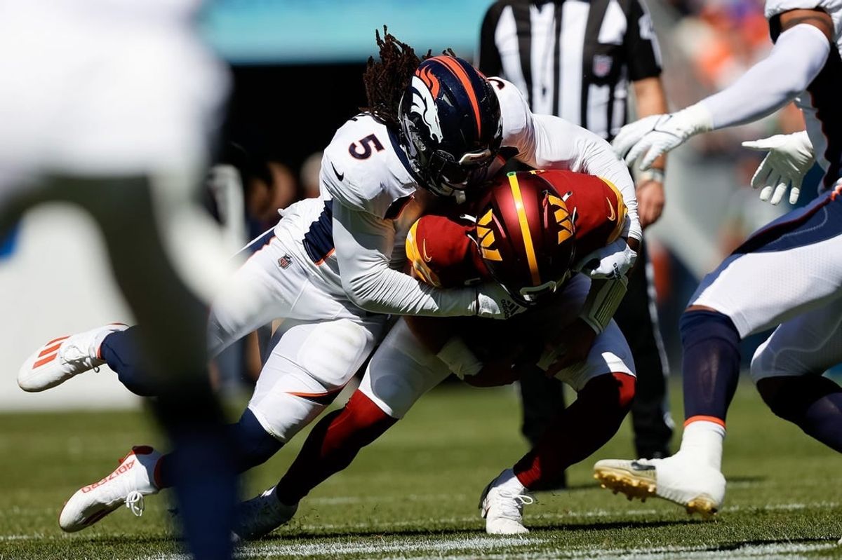 Sep 17, 2023; Denver, Colorado, USA; Washington Commanders quarterback Sam Howell (14) is sacked by Denver Broncos linebacker Randy Gregory (5) in the first quarter at Empower Field at Mile High.